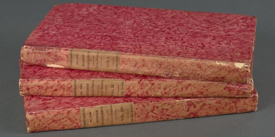 Stack of three volumes of the first edition of Frankenstein, bound in red floral covers.
