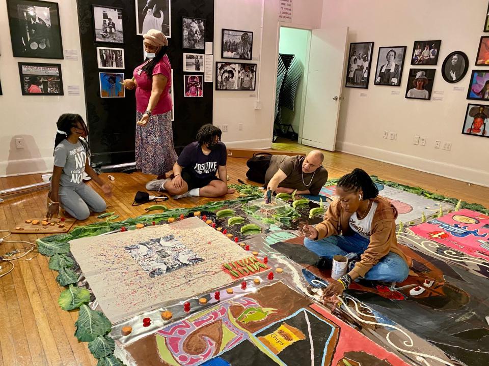 M. Scott Johnson, Junior Scholars students, and a parent of  students work on a collage on the floor of the Center’s American Negro Theatre. It is paintings created by students.