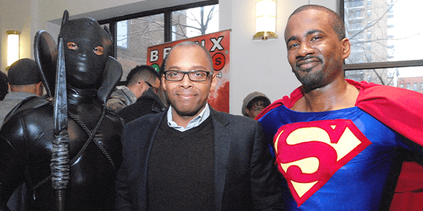 Michael Flood, dressed as Superman in a red cap and blue shirt (right) is pictured with fellow cosplayer Bill Johnson, dressed a Black Panther, and then Schomburg Center Director Khalil Gibran Muhammad, wearing a black blazer &seater, white shirt in 2013