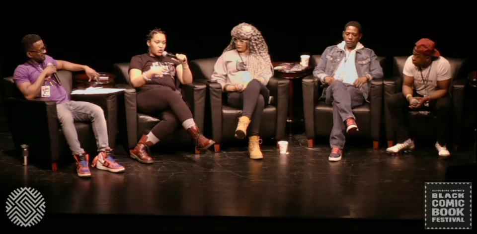 Michael Flood is sitting on stage at Schomburg Center with four other panelists. All are sitting in chairs holding microsphones. 