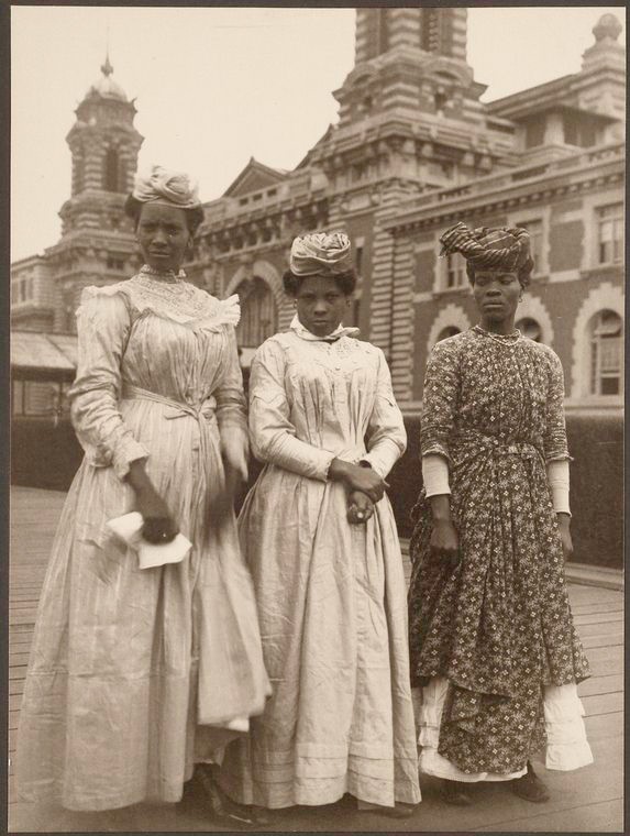 Three women in long, billowing dresses and wearing hats