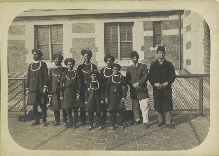 Group photograph of newly-arrived immigrants in native costumes, some with turbans, some with fezzes.