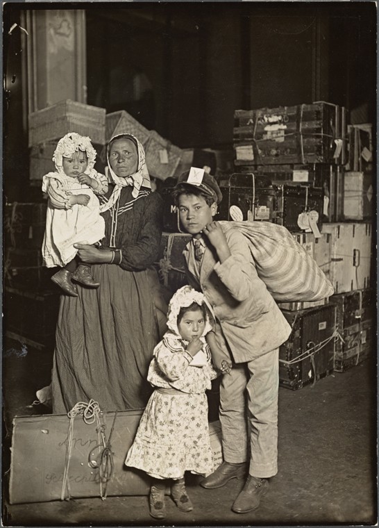 a woman, baby and two children surrounded by luggage