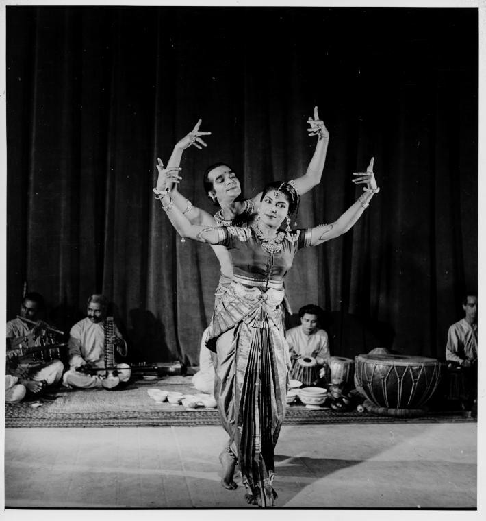a man and woman in Indian dress dance with their hands in the air and fingers pointed