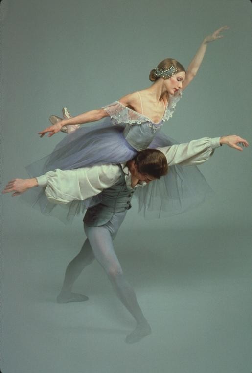 man and woman ballet dancers. woman is balanced on man's back.