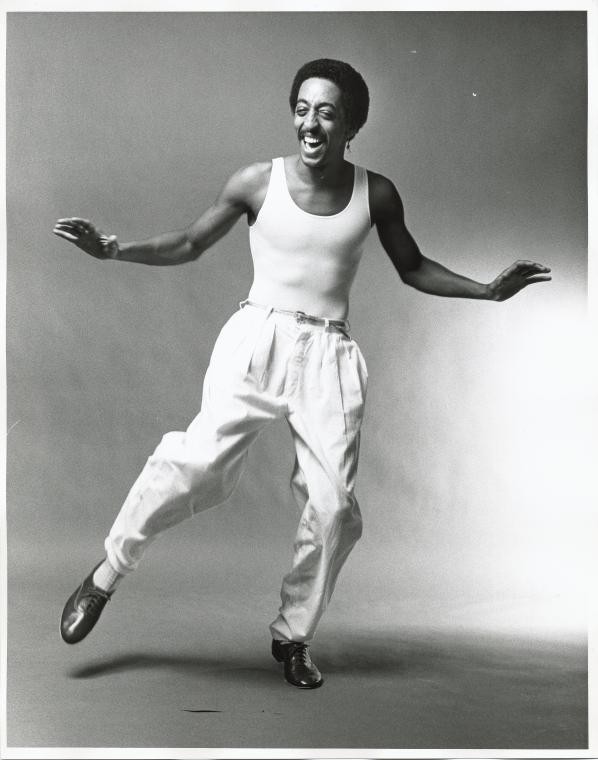 Gregory Hines dressed in white pants and white tank top dancing