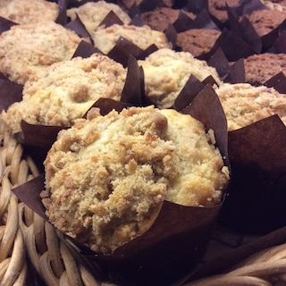 Photo of various muffin flavors wrapped in brown paper and arranged in a wicker basket.