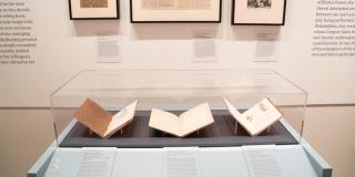 installation view of the exhibition featuring a vitrine with three books and three framed items