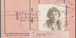 A pink passport page with a torn ragged edge shows a black-and-white photograph of a woman with short hair wearing a coat with a fur collar, a slip of paper signed "Virginia Woolf," and a stamp reading "Foreign Office, 22 Mar 1923." 