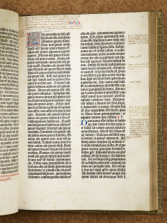 A Gutenberg Bible displayed open to show closely printed text in Latin in two columns, featuring an illuminated letter in the top left corner along with various handwritten annotations in the margins.