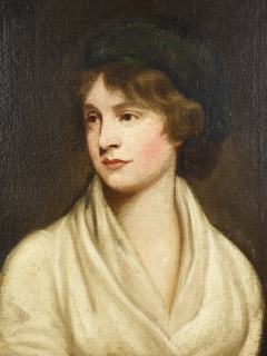 A portrait of a white woman from the bust upwards, set against a dark neutral background.