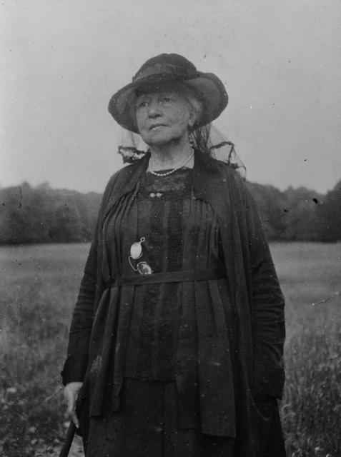 Black and white photo of Lady Gregory standing in a field, wearing all black
