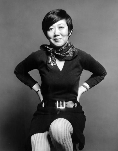 A Korean American woman smiles at the camera and places both her hands on her hips