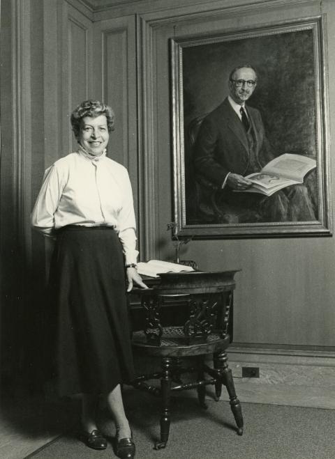 Lola Szladitz standing next to Dickens' desk and a portrait of Albert A. Berg