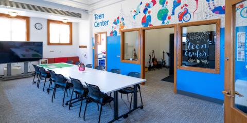 Teen Center at Mott Haven Library, featuring a central work table, a smart board, and audio recording studio.